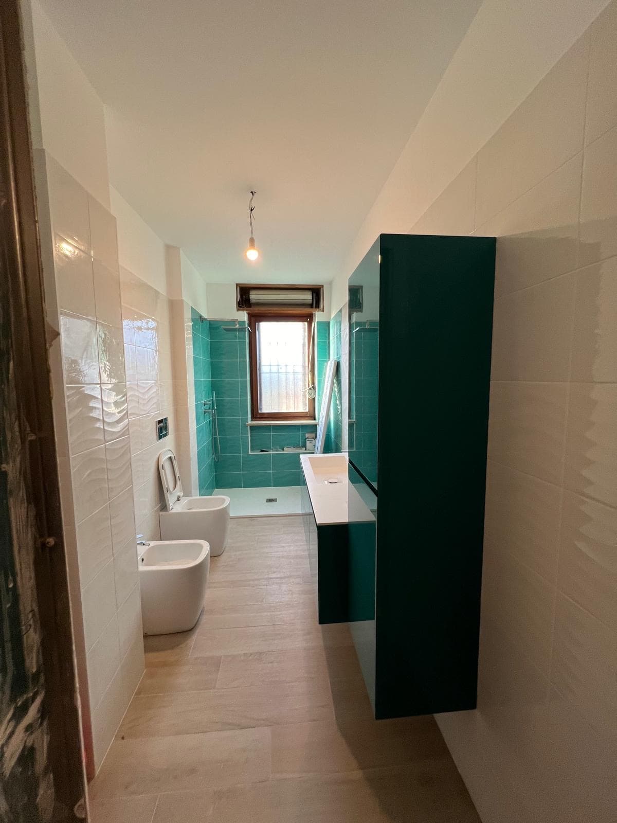 Bagno moderno con rivestimenti bianchi e dettagli verde petrolio